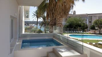 Relax by the pool surrounded by lush gardens and a historic building.