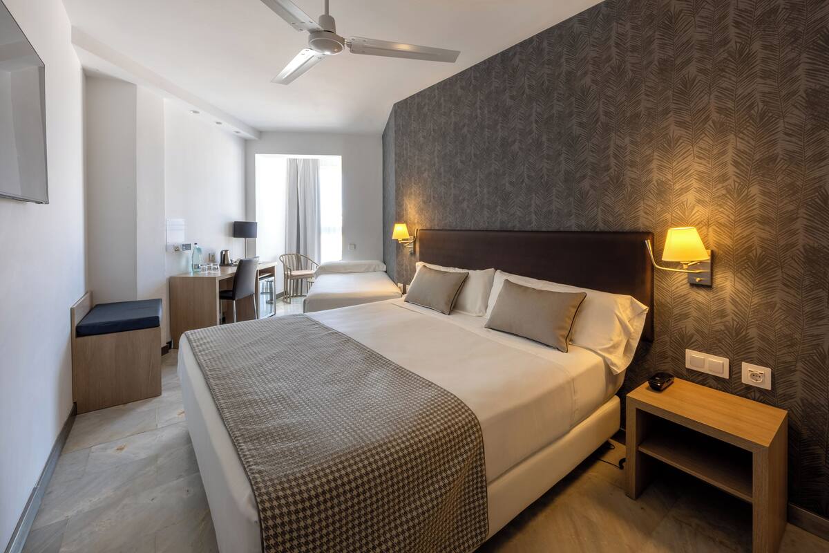 A hotel room with a large bed, bedside lamps, a desk, and a chair.