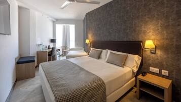 Habitació d'hotel amb un llit gran, tauletes de nit, escriptori i una cadira.