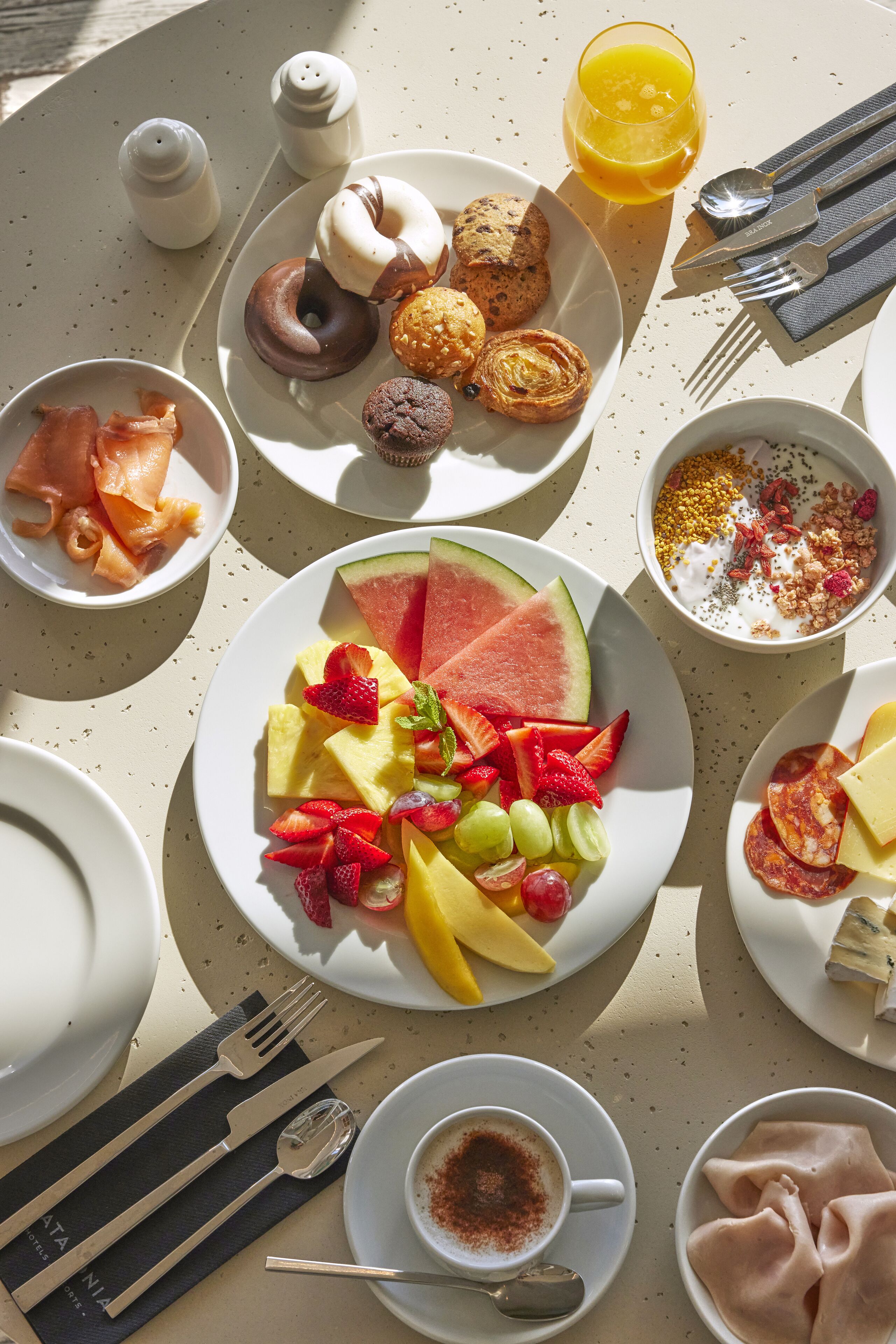 A breakfast setting with various dishes including fruits, pastries, and beverages.