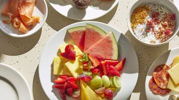 A breakfast setting with various dishes including fruits, pastries, and beverages.