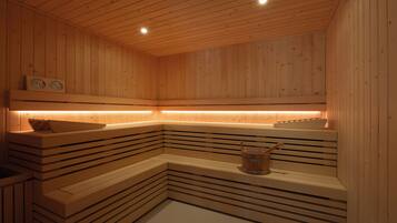 Una sauna in legno con panche e un catino.