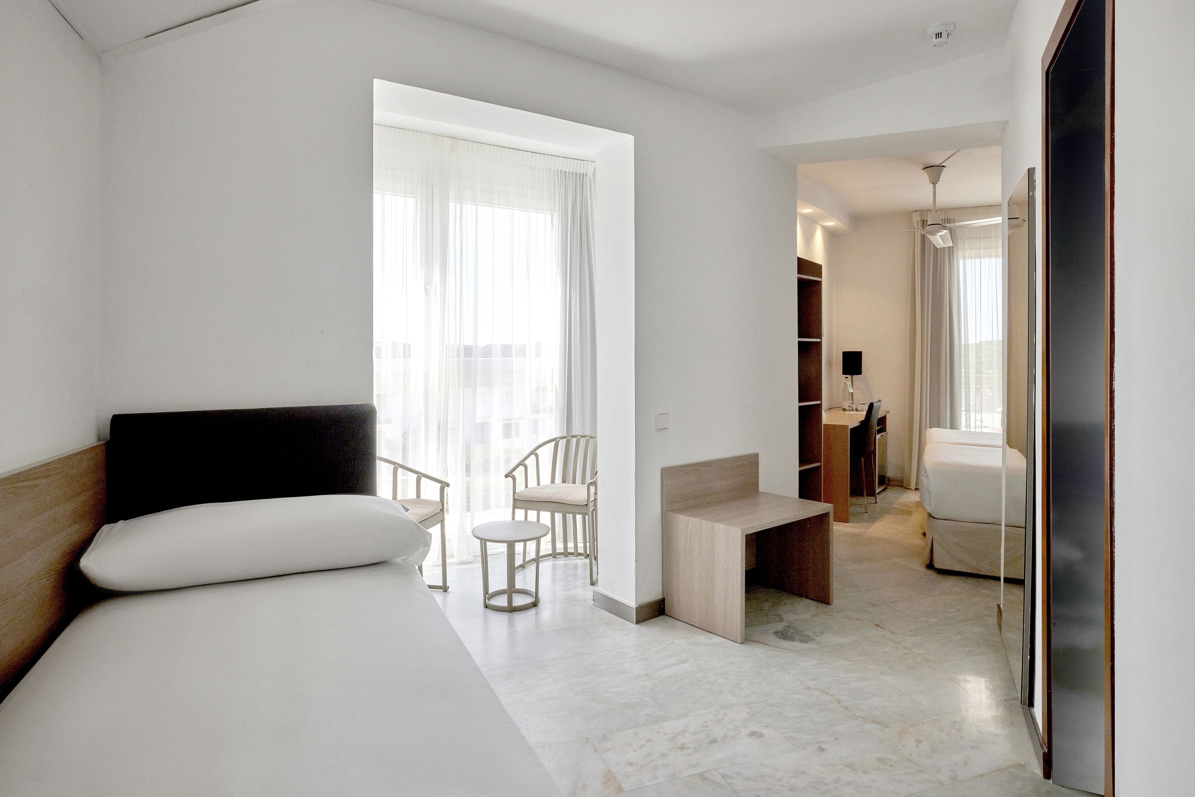 Una habitación de hotel moderna con cama, escritorio, silla y armario.