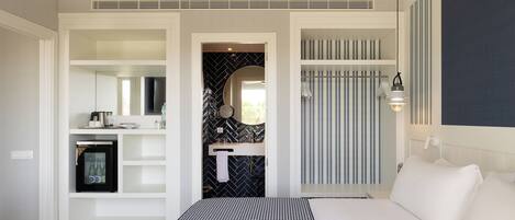 A bedroom with a bed, a wardrobe, a mirror, and a sink.