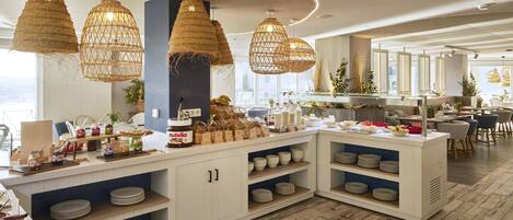 Una cocina moderna con una isla central, lámparas colgantes de ratán y una variedad de alimentos y utensilios.