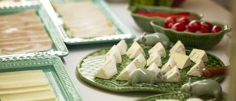 Una mesa de buffet con diversas opciones de comida, incluyendo queso, frutas y verduras.