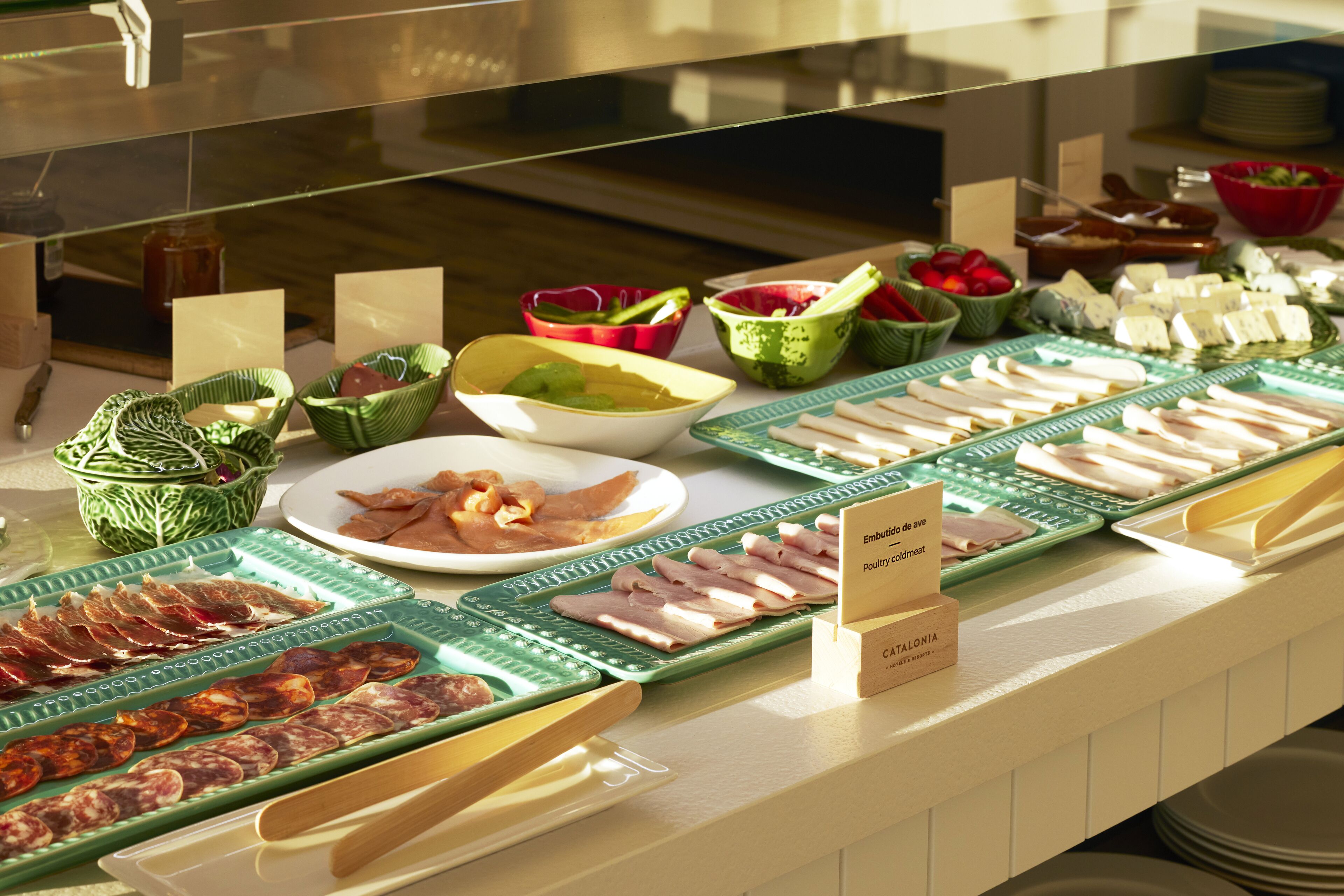 A buffet with various food items including meats, cheeses, and fruits.