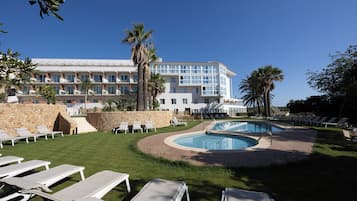 Een seizoensgebonden buitenzwembad en ligstoelen