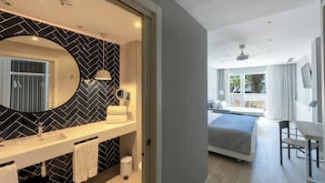 Habitación de hotel moderna con un espejo grande, una cama doble, un escritorio y vistas al exterior.