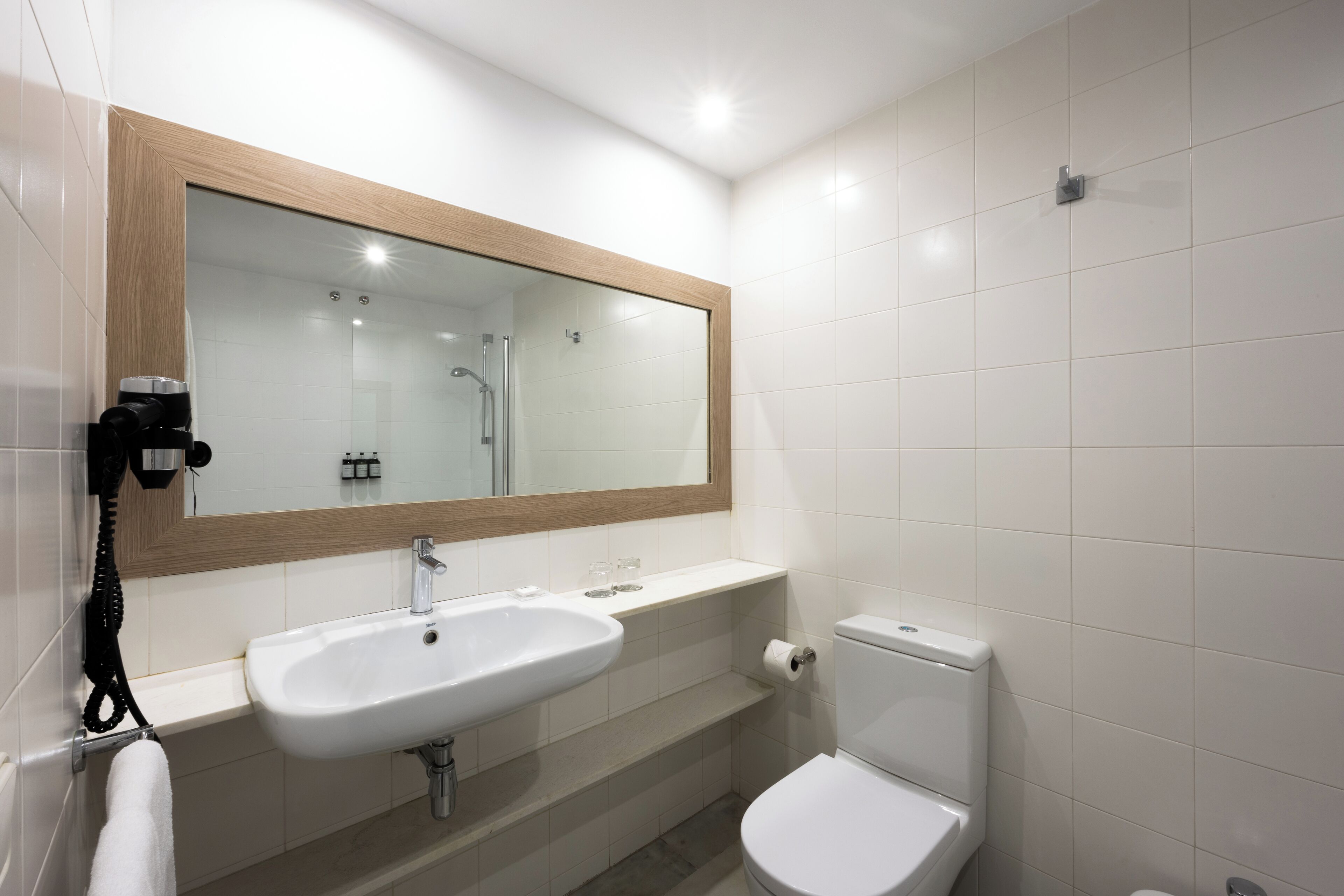 Een moderne badkamer met een witte wastafel, spiegel en toilet.