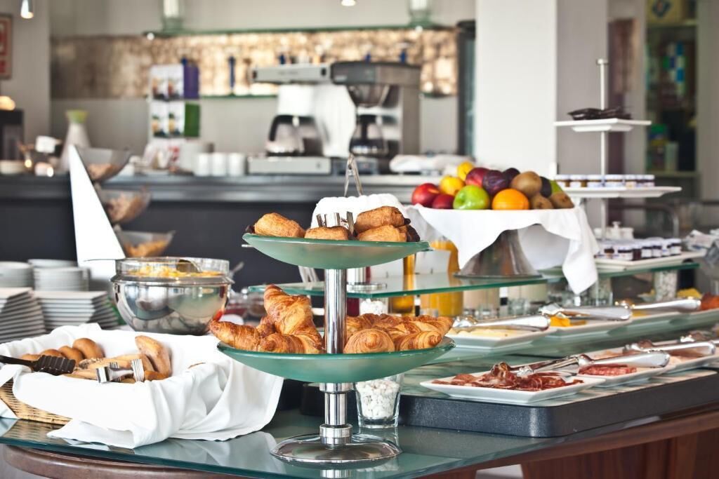 A buffet with various food items including pastries, fruits, and condiments.