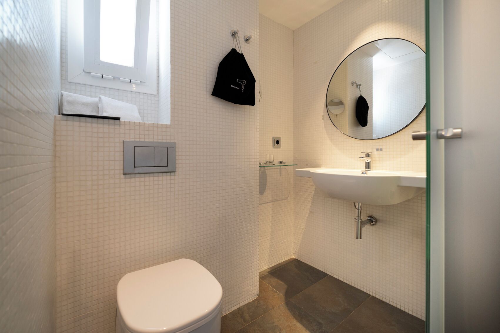 A modern bathroom with a toilet, sink, and mirror.