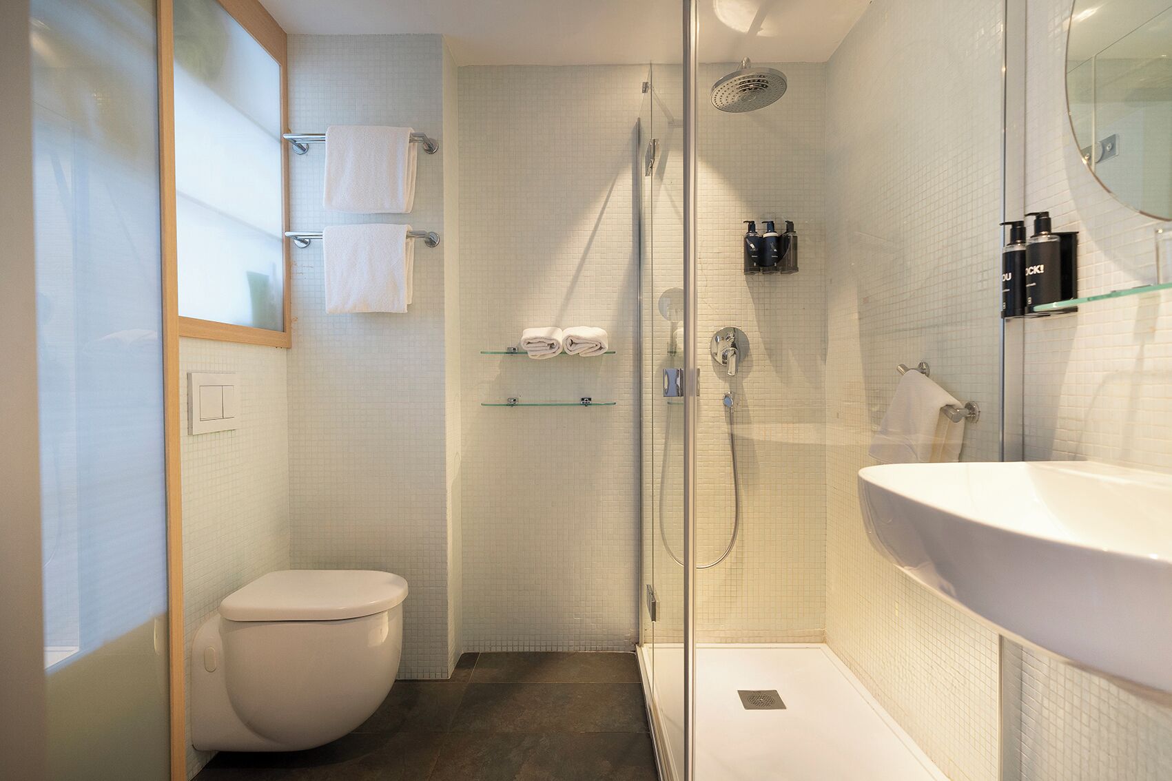 Une salle de bain moderne avec une douche à parois de verre, des toilettes blanches et un grand lavabo.