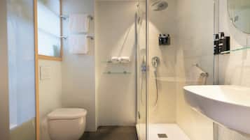 Un baño moderno con ducha de vidrio, inodoro blanco y un lavamanos grande.