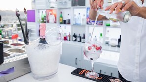 A bartender pouring a drink into a glass with a bottle of alcohol and ice in a bucket. - Ocean Drive Ibiza (Ibiza Town)