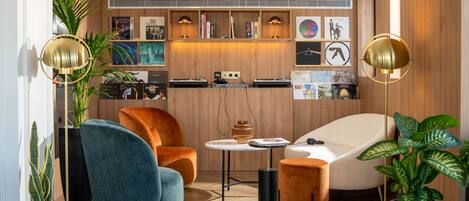 Ein modernes Wohnzimmer mit einer Holzvertäfelung, einem weißen Sofa, einem blauen Sessel und einem kleinen runden Tisch.