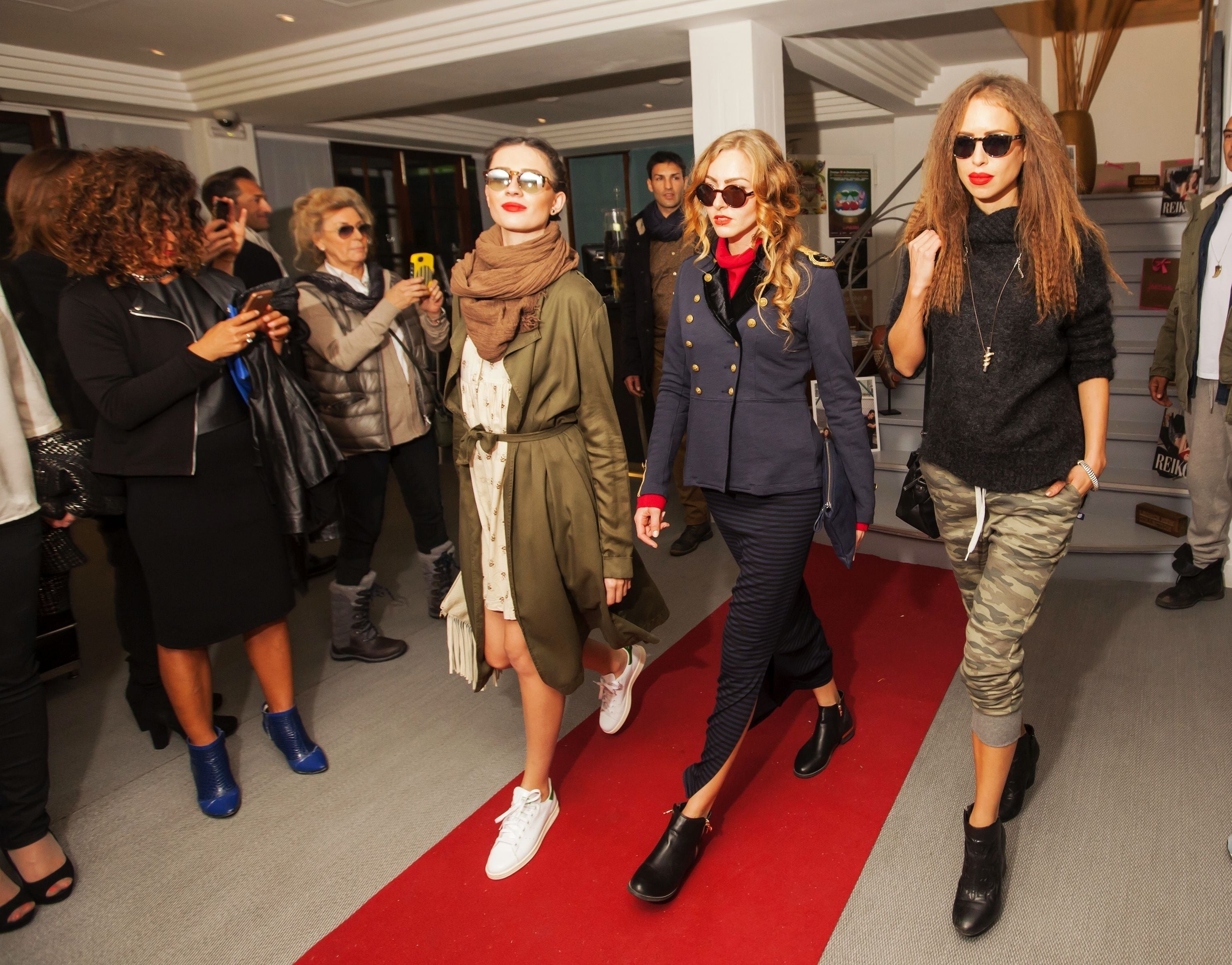 A group of people walking on a red carpet inside a building.
