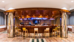 A bar area with a curved wooden counter, bar stools, and a barista behind the counter.