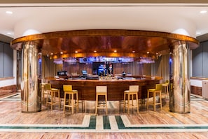 A bar area with a curved wooden counter, bar stools, and a barista behind the counter.