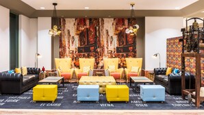 A modern lounge area with leather sofas, colorful ottomans, and a large abstract mural on the wall.