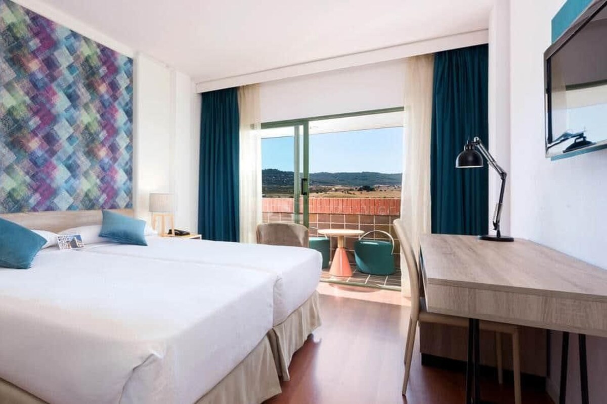 Une chambre d’hôtel avec un grand lit, un bureau et un balcon offrant une vue agréable.