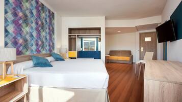 A modern hotel room with a large bed, a desk, a chair, and a TV.