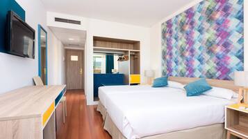 Una habitación de hotel con una cama, un escritorio, un televisor y una pared de colores.
