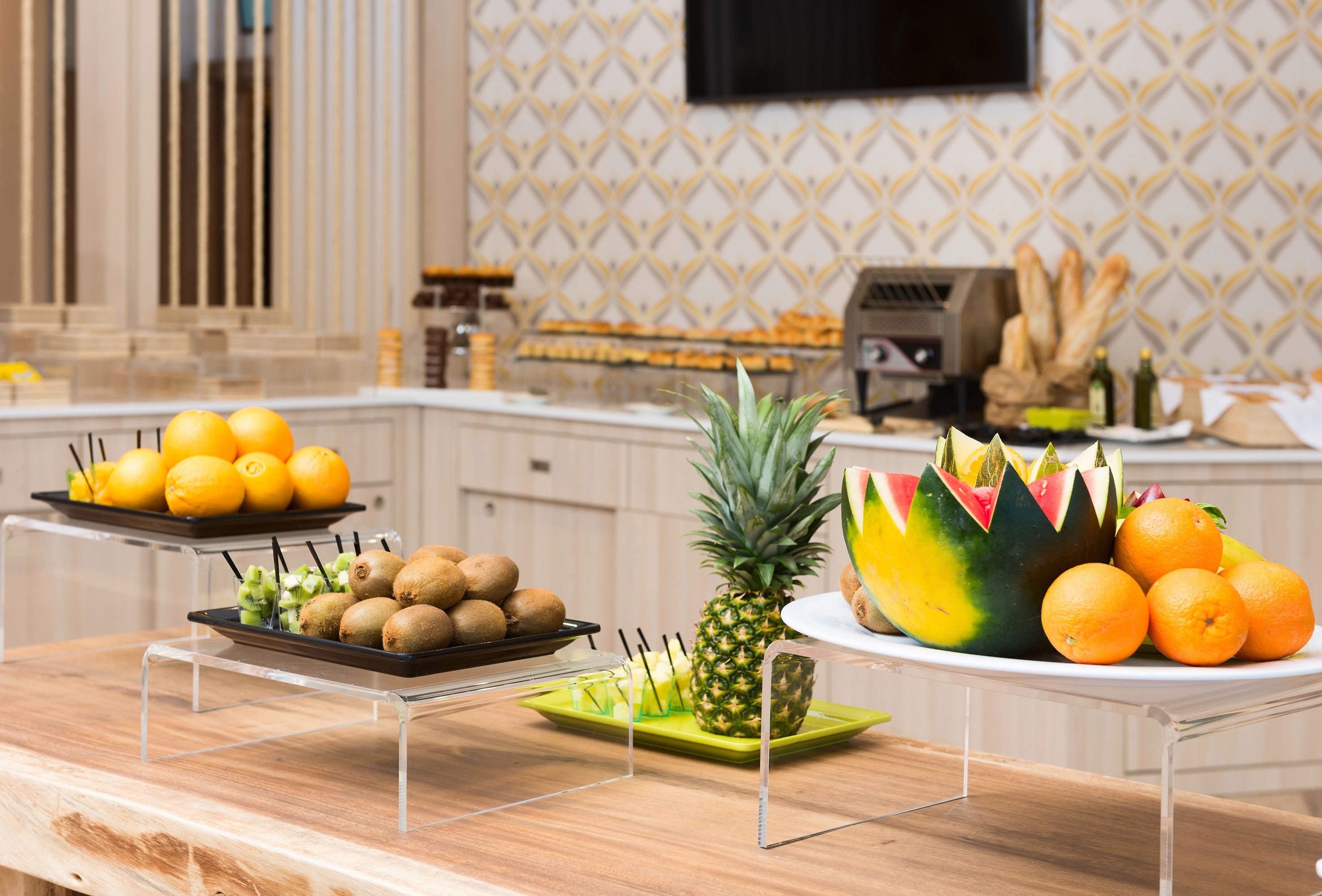 Una encimera de cocina con frutas y verduras exhibidas en soportes transparentes.