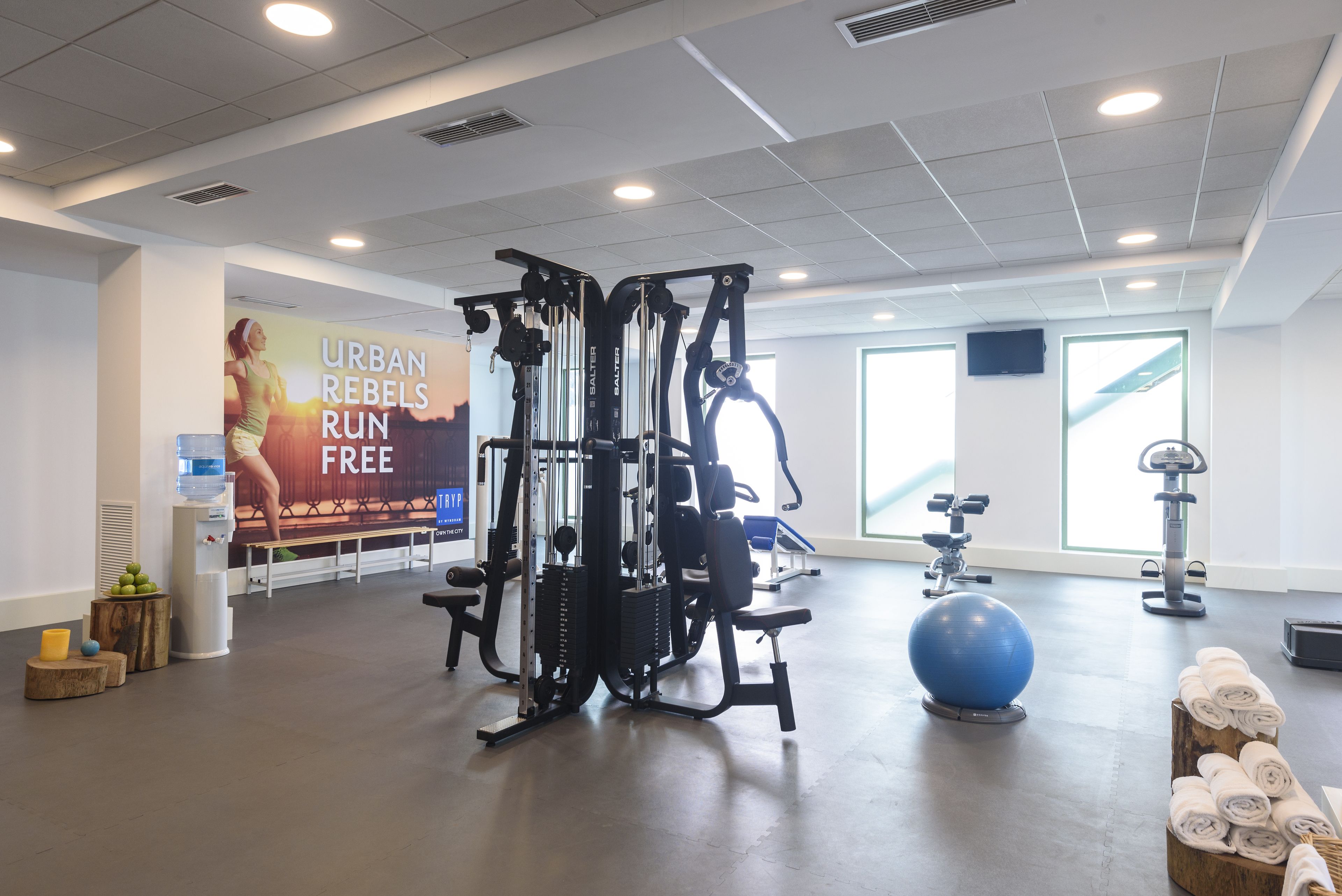 A gym with exercise equipment, a water dispenser, and a wall advertisement.