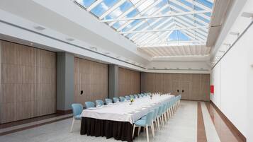 A conference room with a long table, light blue chairs, and a high ceiling with a skylight.