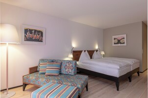 Un dormitorio con una cama, un sofá y dos lámparas de pared.