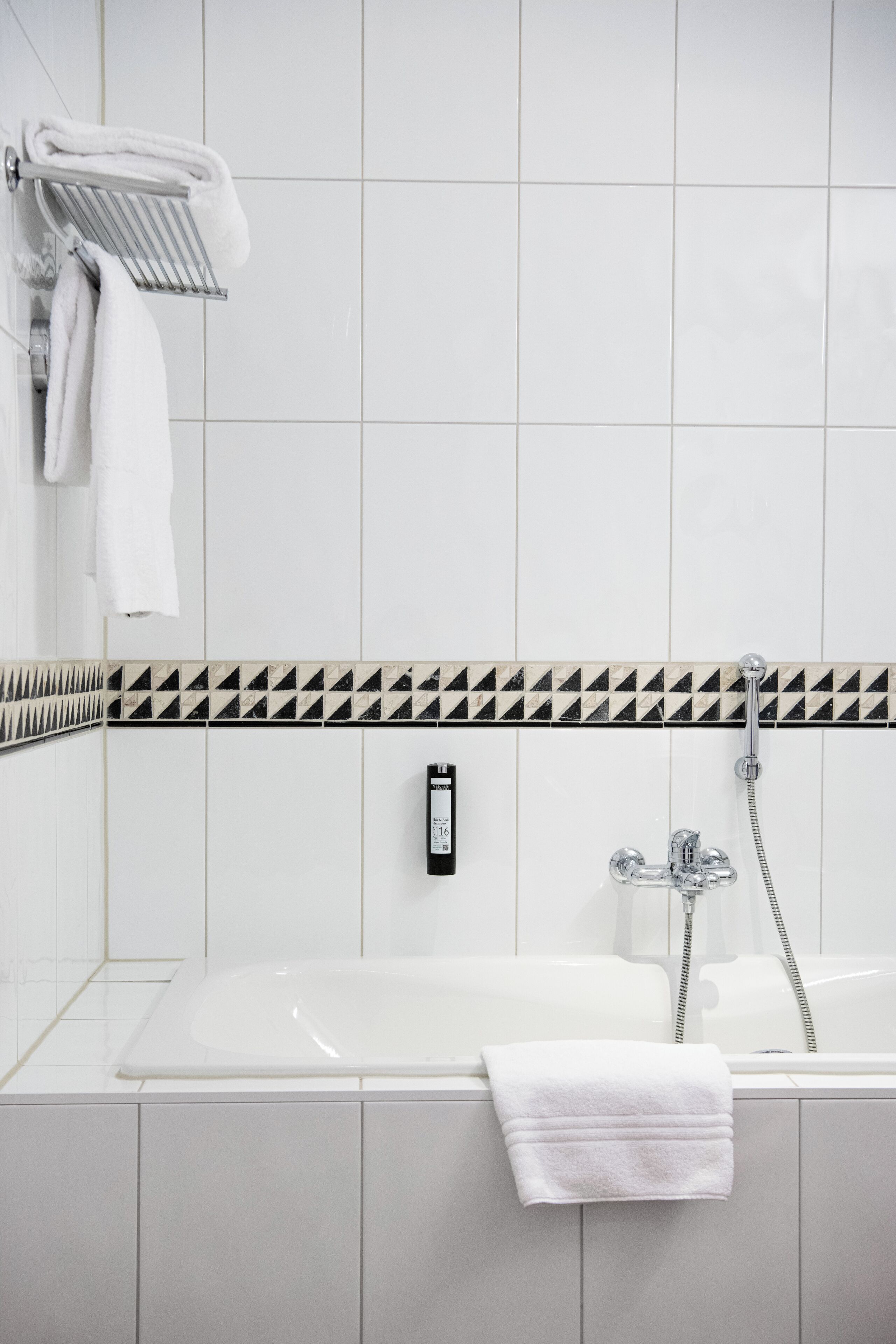 A modern bathroom with a white bathtub, a towel rack, and a shower head.