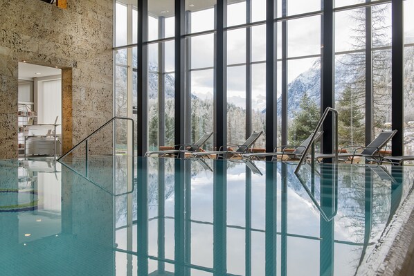 Una piscina cubierta, una piscina al aire libre, tumbonas