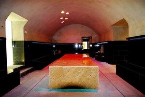 Un interior espacioso y moderno con una plataforma rectangular central, techos altos y una paleta de colores cálidos.