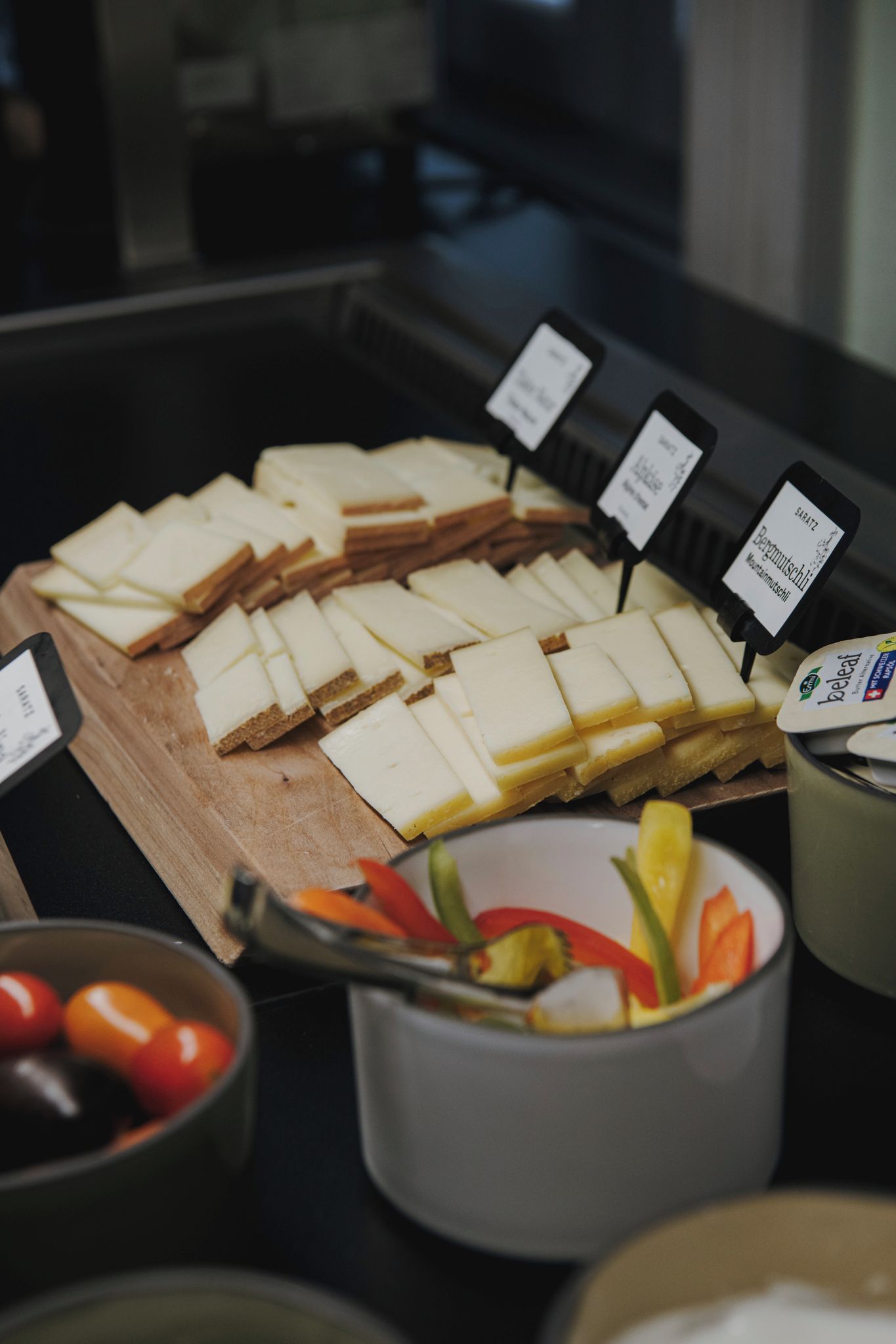 Un bufé con diversas opciones de comida, incluyendo pan en rebanadas, queso y un tazón de fruta.