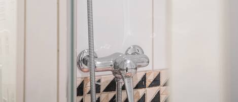 Ducha con cabezal de ducha de mano y grifo empotrado en la pared.