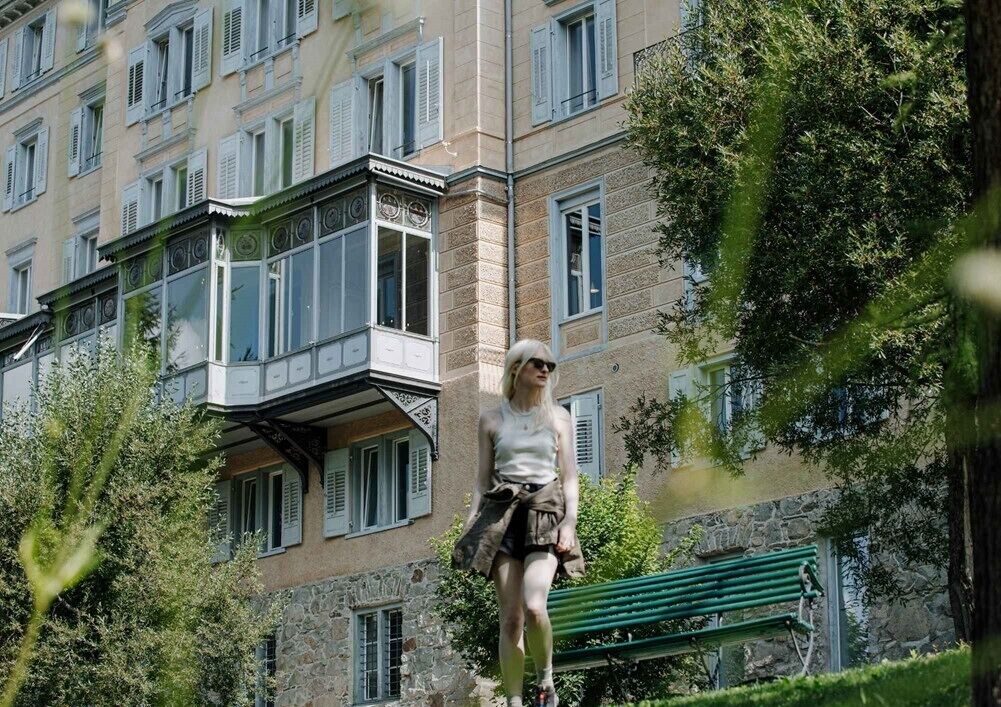 Una persona de pie frente a un edificio con varias ventanas y balcones.