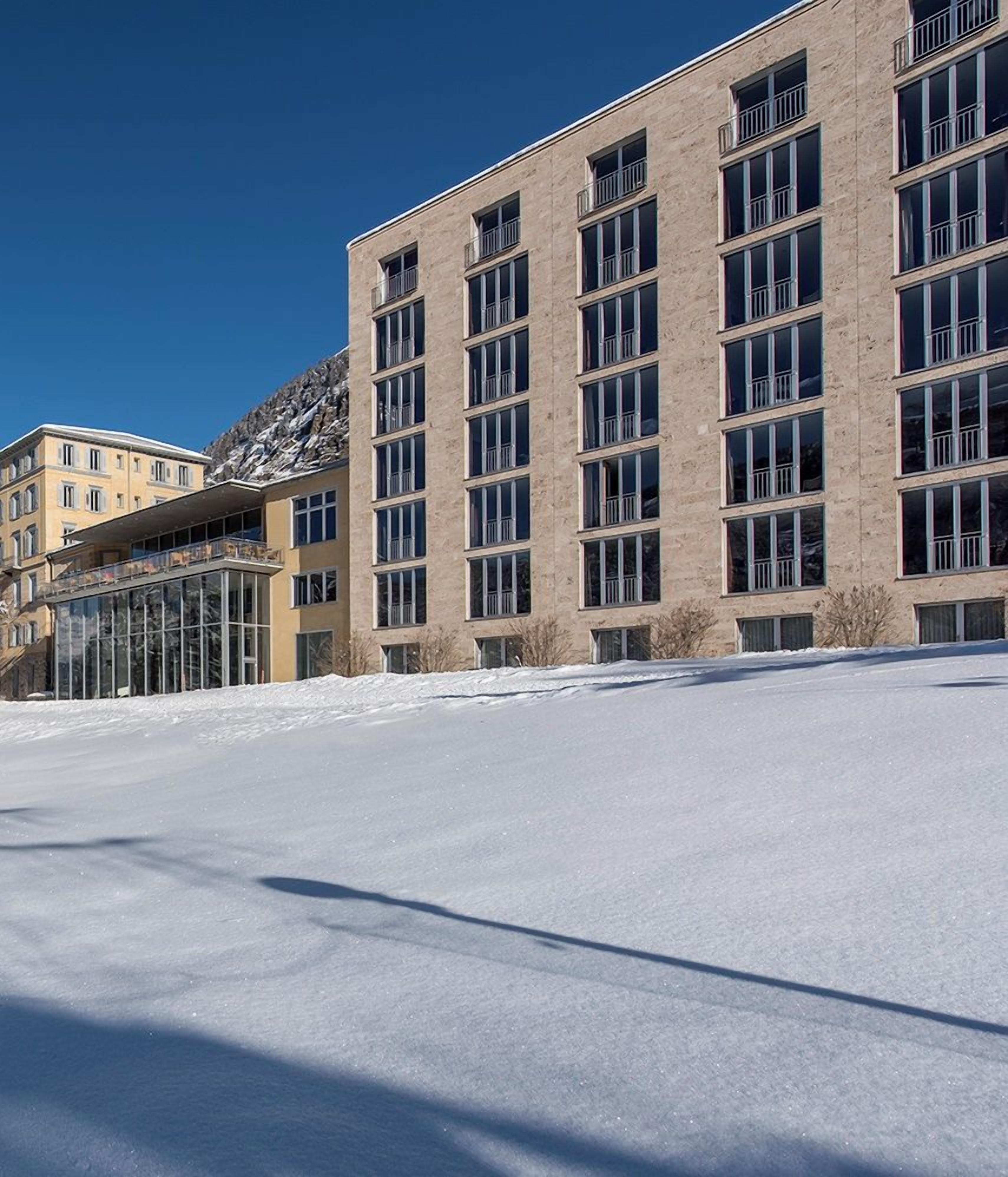 Ein Gebäude mit vielen Fenstern und verschneitem Untergrund.