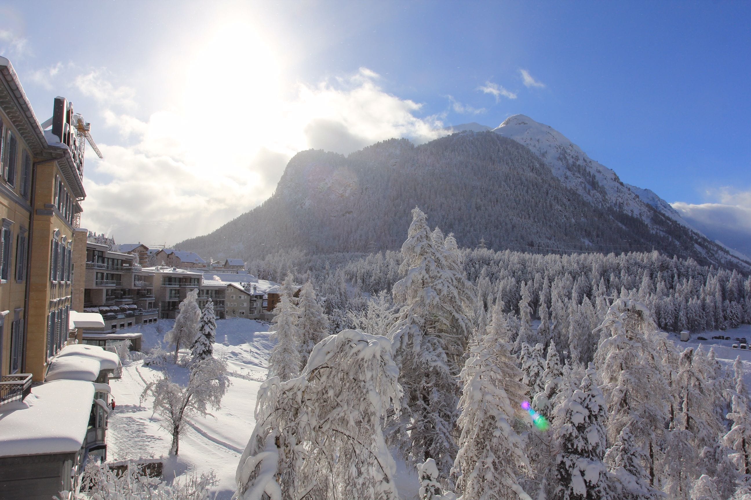 Une montagne aux arbres couverts de neige et un bâtiment doté de balcons.