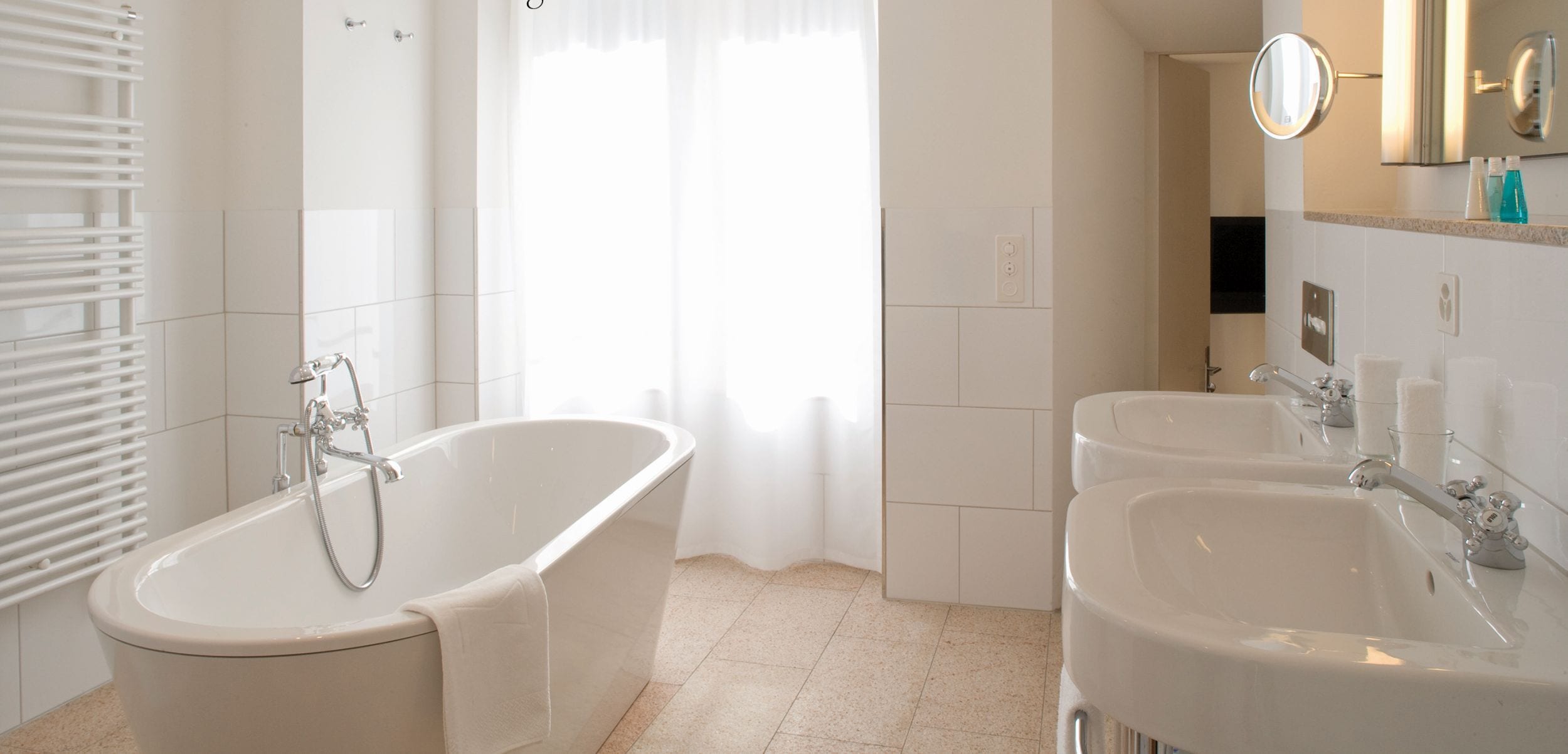 A modern bathroom with a freestanding bathtub, two sinks, and a large mirror above the mirror cabinet.