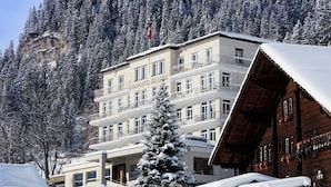 A multi-story hotel with balconies and a snow-covered mountain backdrop. - Bellevue Parkhotel & Spa - Relais & Châteaux (Adelboden)