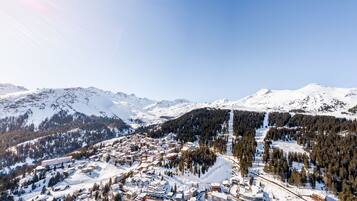 A snow-covered mountain town with buildings and ski slopes.