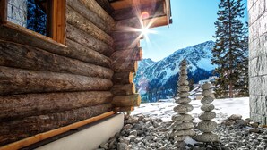 Una cabaña de troncos con un muro de piedra y un montículo de piedras en la nieve.