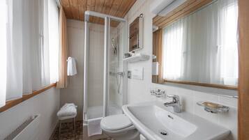 Un baño con ducha, inodoro, lavabo y un espejo grande.