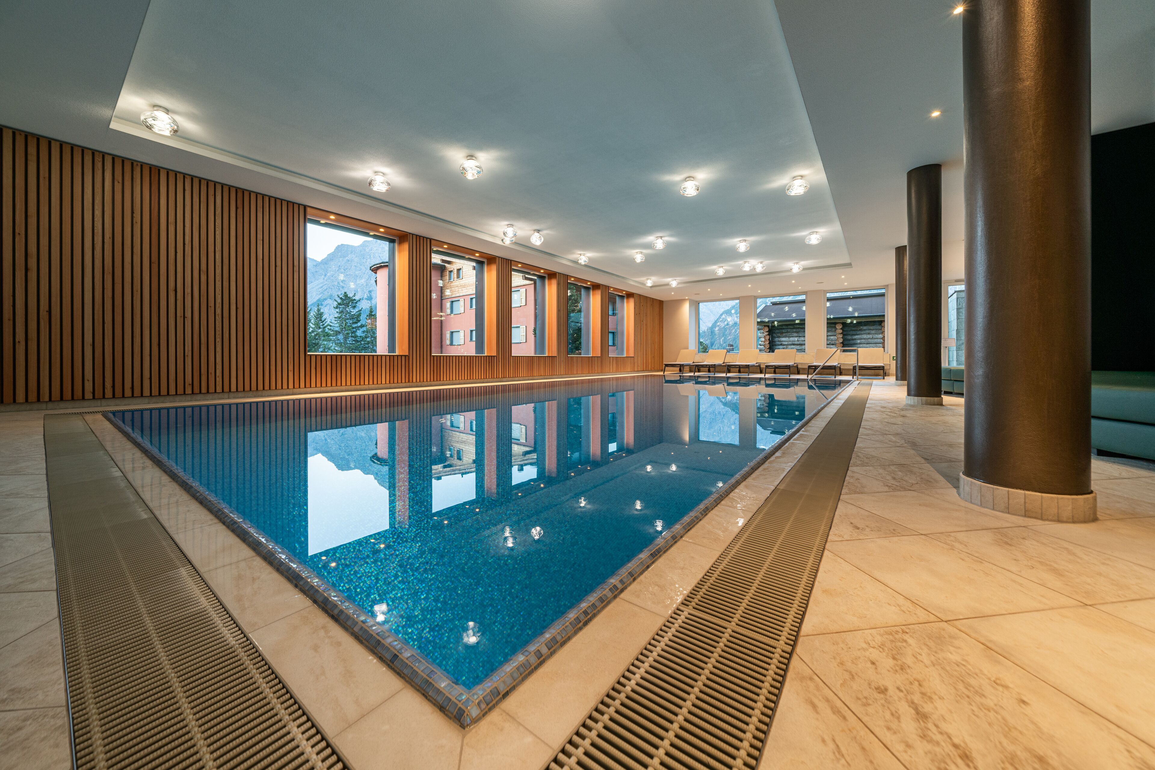 Piscina interior moderna con vistas despejadas a las montañas a través de amplias ventanas.