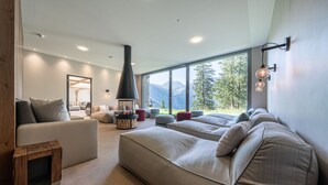 Una sala de estar moderna con chimenea, ventanas amplias y vistas a montañas.