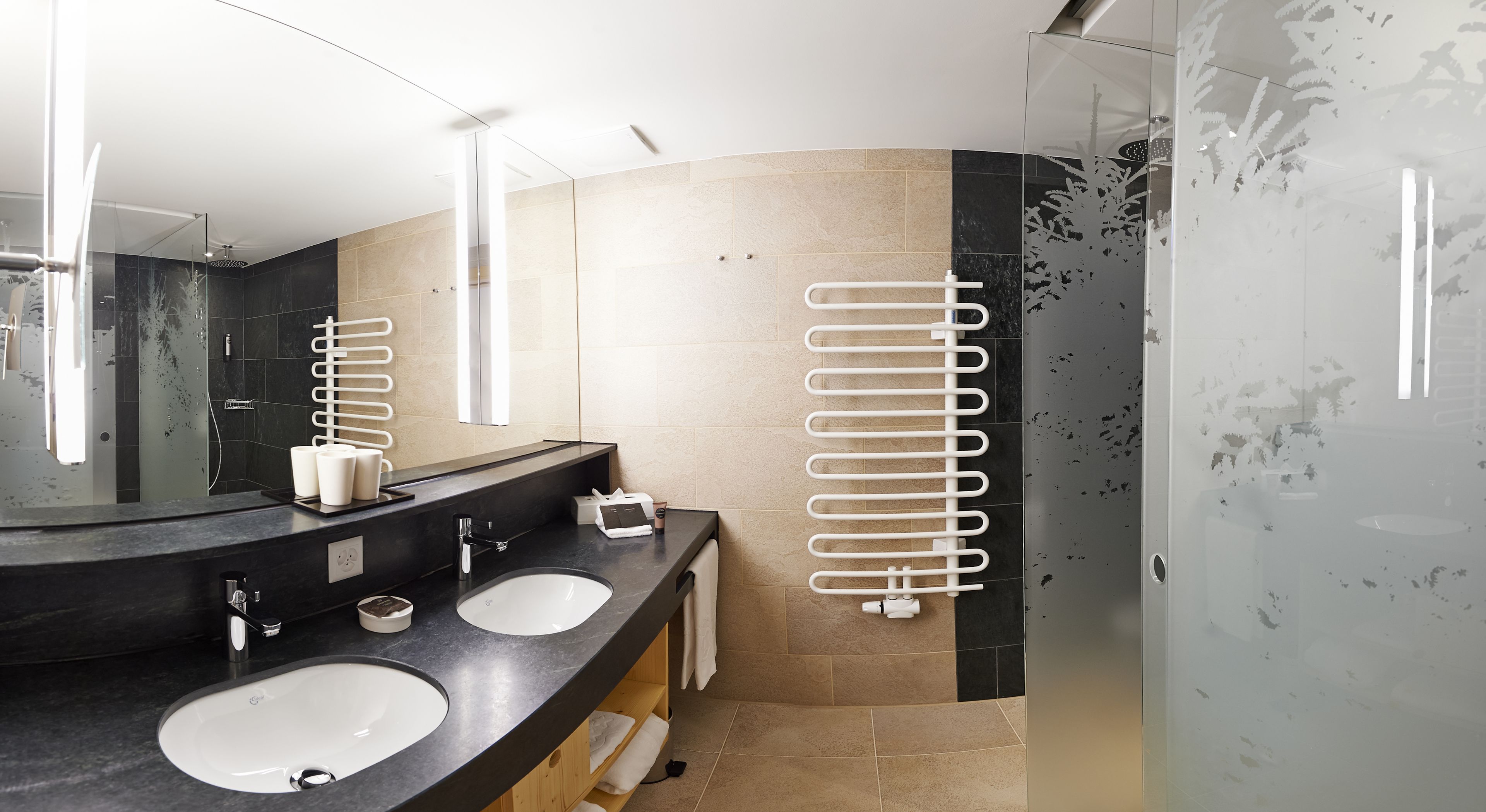 A modern bathroom with two sinks, a large mirror, and a glass shower enclosure.