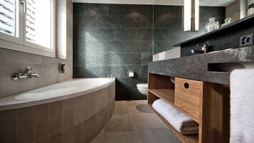 A modern bathroom with a freestanding bathtub, a wooden vanity, and a large mirror.