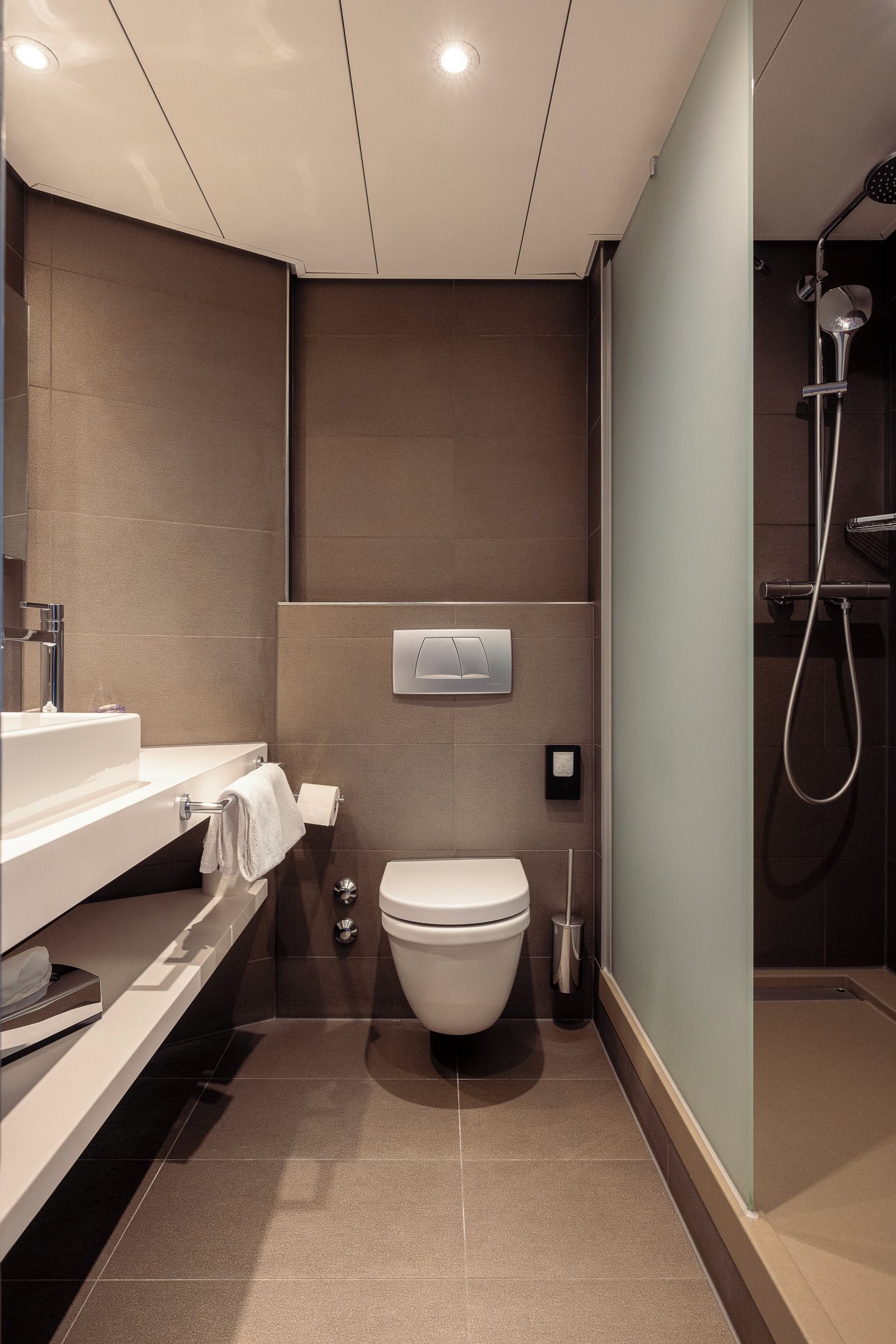 A modern bathroom with a toilet, sink, and shower.