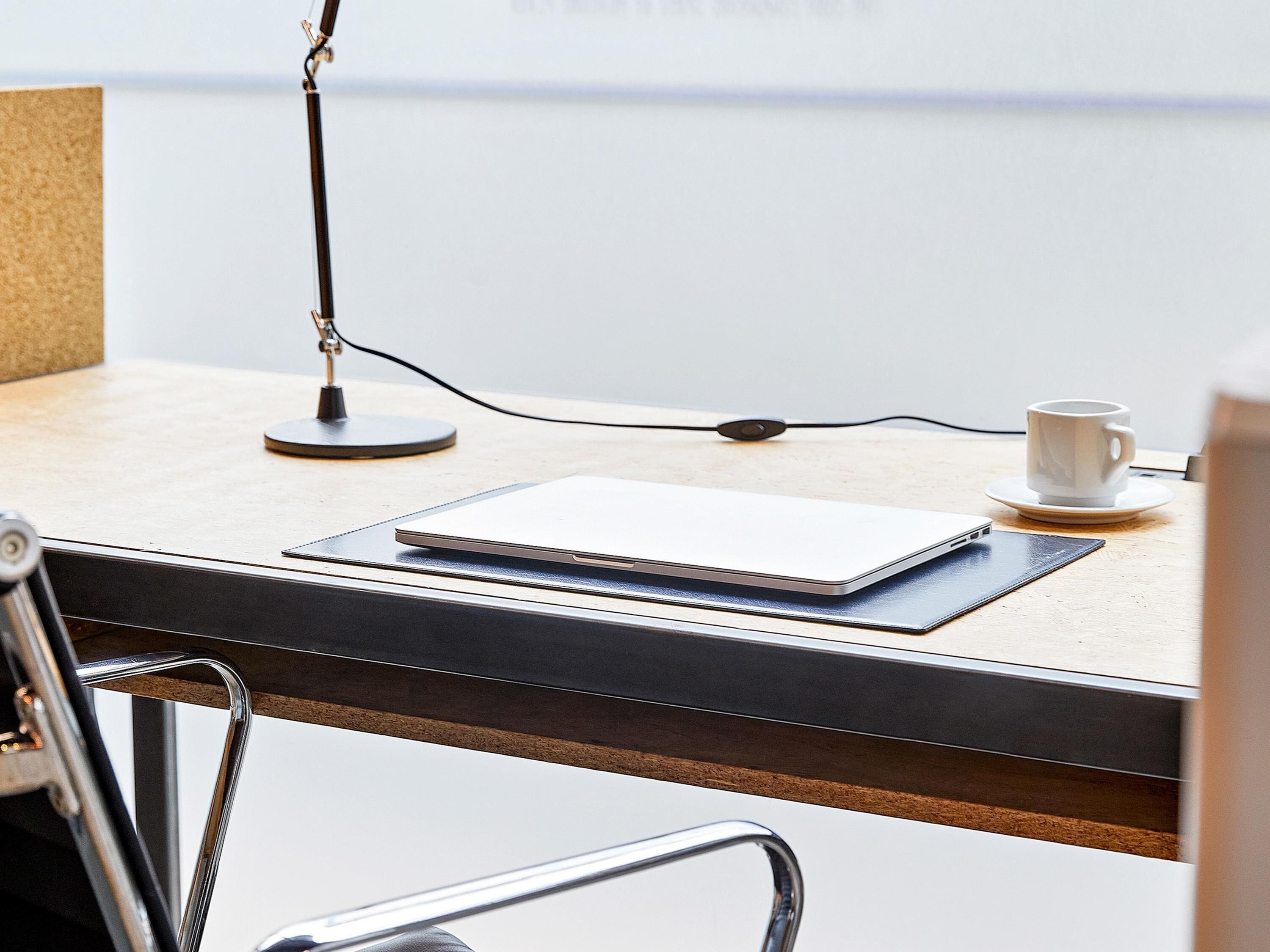 Ein Schreibtisch mit einem Laptop, einer Tasse und einer Lampe.